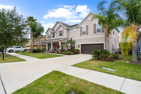 Spacious Tampa home exterior with lush landscaping and palm trees in a vibrant residential neighborhood.