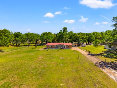 Spacious rural property with a large mobile home and ample green yard, ideal for country living and outdoor activities.