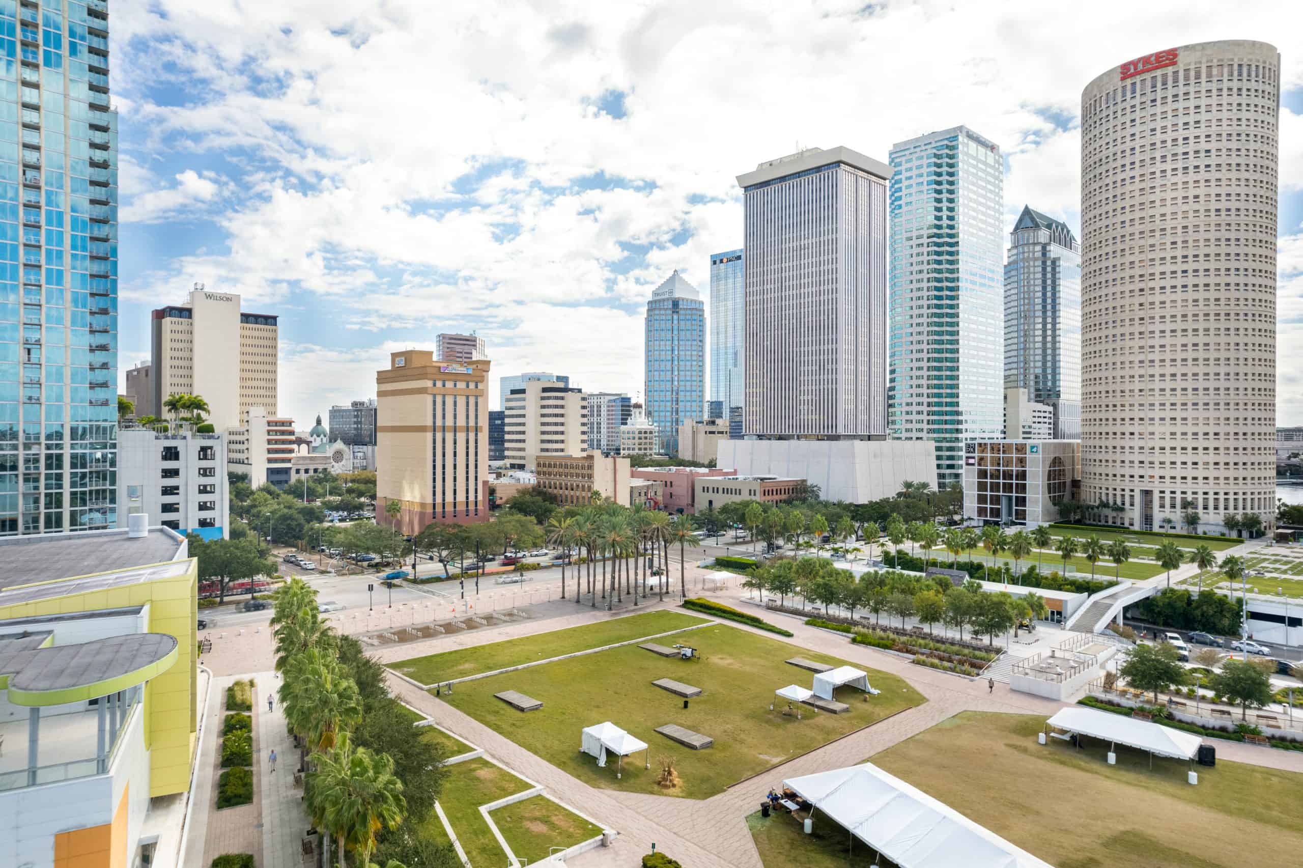Modern Tampa skyline with tall office buildings and a spacious city park, vibrant and bustling urban area.